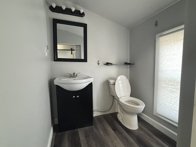 bathroom featuring hardwood / wood-style flooring, toilet, vanity, and vaulted ceiling