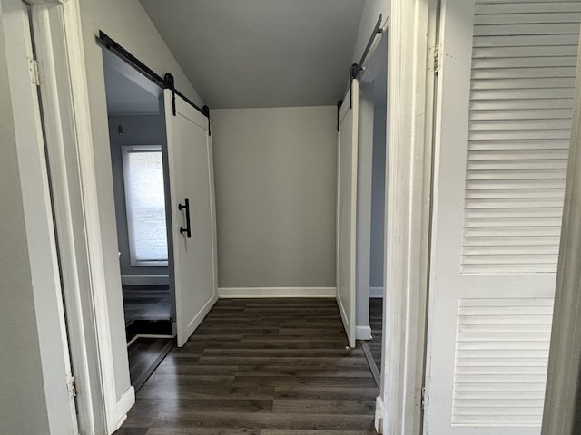 hallway with dark wood-type flooring and a barn door