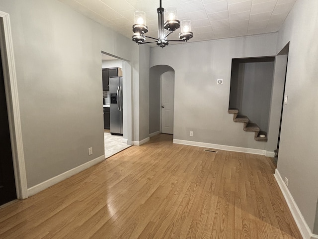 unfurnished dining area featuring light wood-type flooring and an inviting chandelier