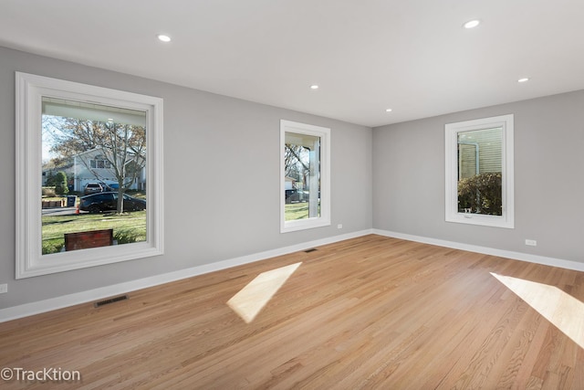 empty room with light hardwood / wood-style flooring and a healthy amount of sunlight