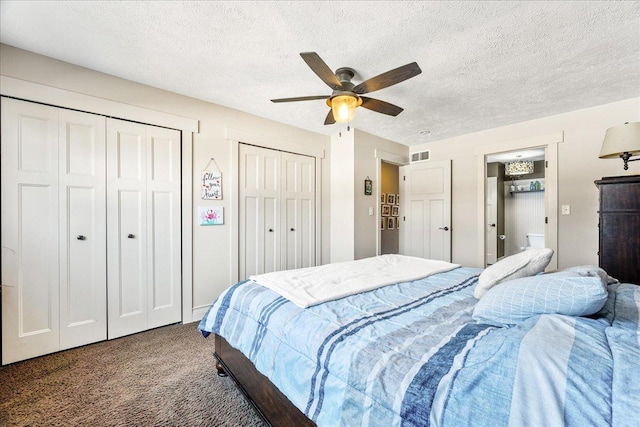 bedroom with ceiling fan, carpet flooring, a textured ceiling, and two closets