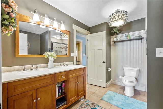 bathroom with a textured ceiling, tile patterned floors, vanity, and toilet