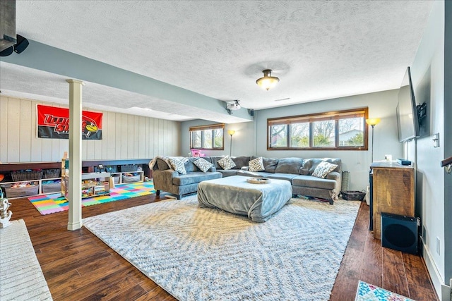 living room featuring wood walls, a textured ceiling, and dark hardwood / wood-style flooring