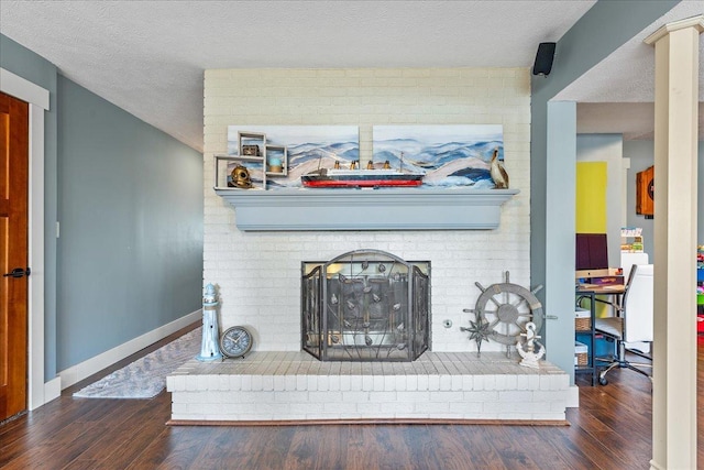 living room with a brick fireplace, dark hardwood / wood-style floors, and a textured ceiling