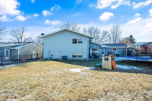 back of property with a playground, a trampoline, central AC unit, and a yard