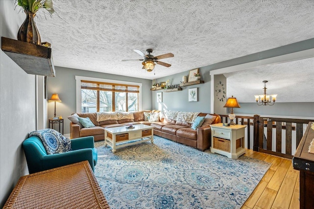 living room with hardwood / wood-style flooring, a textured ceiling, and ceiling fan with notable chandelier