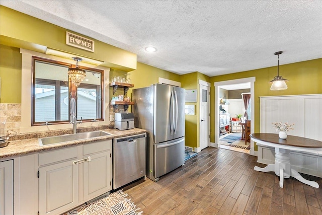 kitchen featuring appliances with stainless steel finishes, a textured ceiling, sink, white cabinets, and pendant lighting