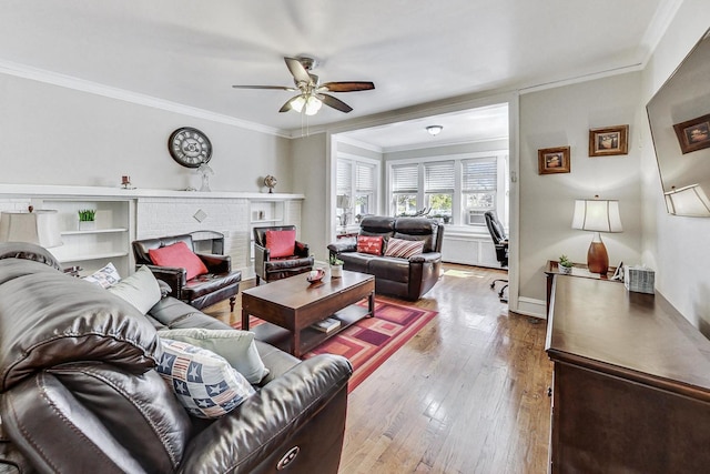 living room featuring ceiling fan, light hardwood / wood-style flooring, a fireplace, and crown molding