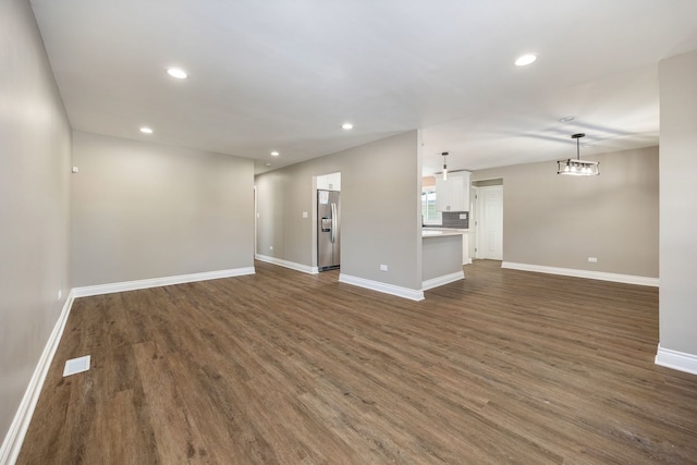 unfurnished living room with a notable chandelier and dark hardwood / wood-style floors