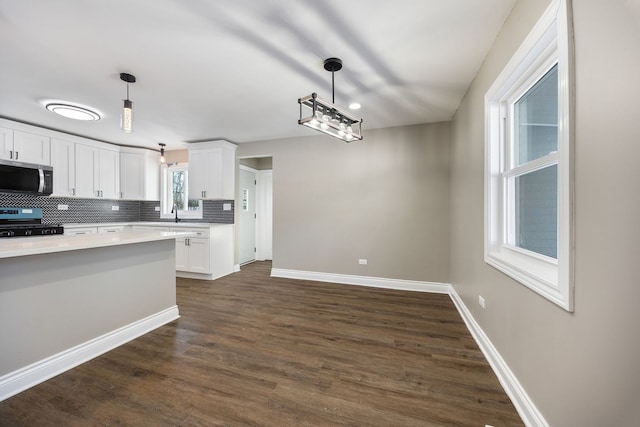 kitchen featuring white cabinets, hanging light fixtures, stove, and decorative backsplash