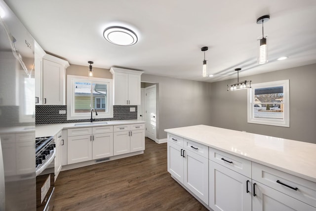 kitchen with white cabinetry, appliances with stainless steel finishes, decorative backsplash, hanging light fixtures, and sink