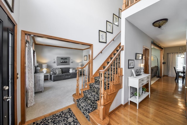 stairway with hardwood / wood-style flooring and a towering ceiling