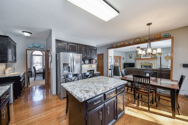 kitchen with stainless steel fridge with ice dispenser, light wood-type flooring, a breakfast bar area, and a kitchen island