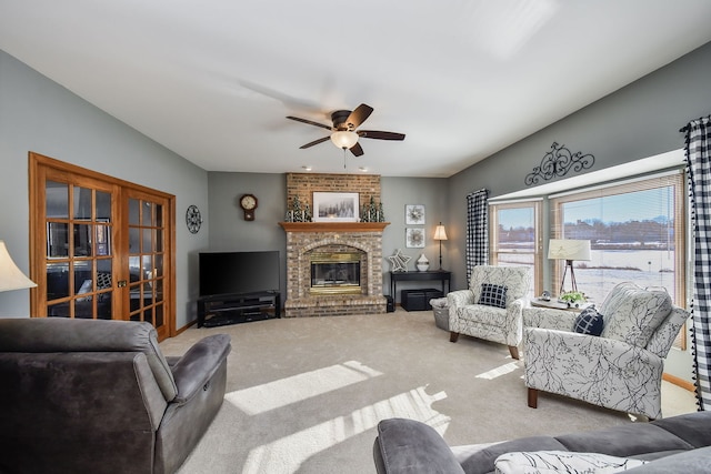 carpeted living room featuring a brick fireplace and ceiling fan