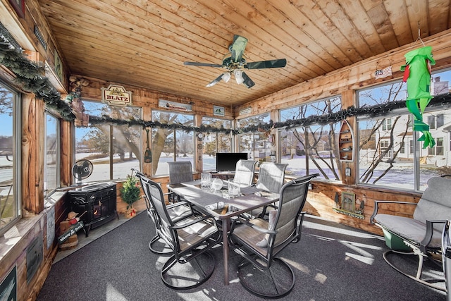 sunroom featuring ceiling fan, a wood stove, and wood ceiling