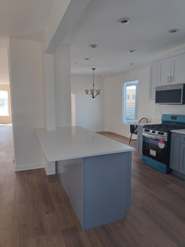 kitchen with light countertops, recessed lighting, wood finished floors, hanging light fixtures, and stainless steel appliances