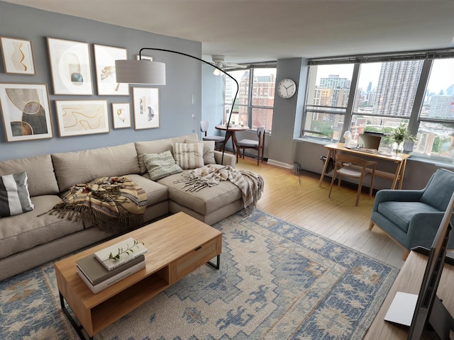 living room featuring wood finished floors, a ceiling fan, and a city view