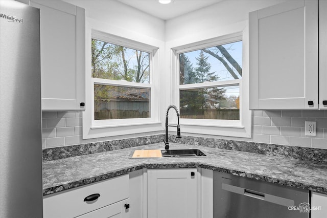 kitchen with sink, white cabinetry, dishwasher, and a wealth of natural light