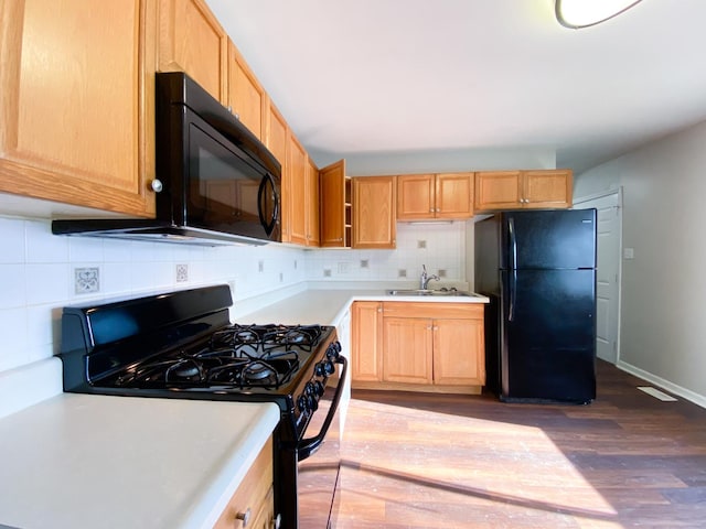 kitchen with light brown cabinetry, sink, dark hardwood / wood-style floors, black appliances, and decorative backsplash