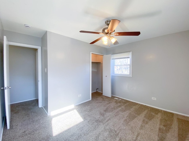 unfurnished bedroom featuring ceiling fan, a spacious closet, a closet, and carpet floors