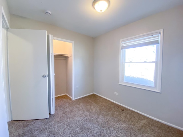 unfurnished bedroom featuring a spacious closet, a closet, and carpet flooring