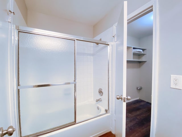 bathroom with hardwood / wood-style flooring and combined bath / shower with glass door