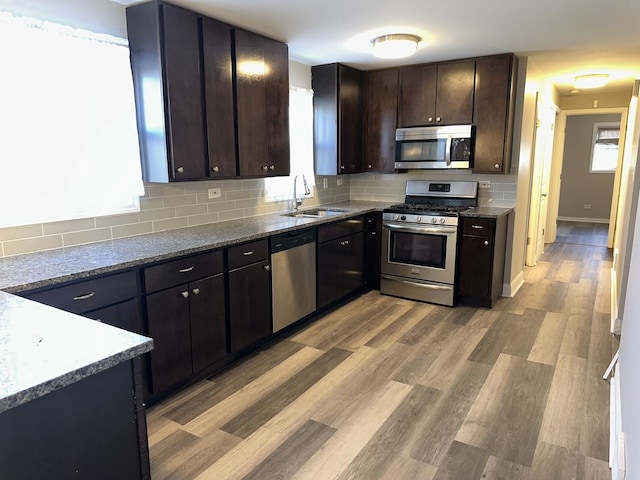 kitchen featuring dark brown cabinetry, stainless steel appliances, tasteful backsplash, sink, and stone counters