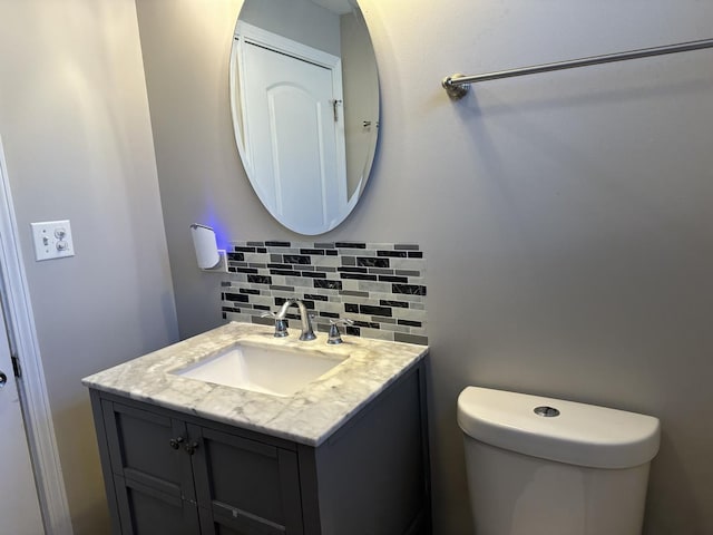 bathroom featuring vanity, toilet, and tasteful backsplash