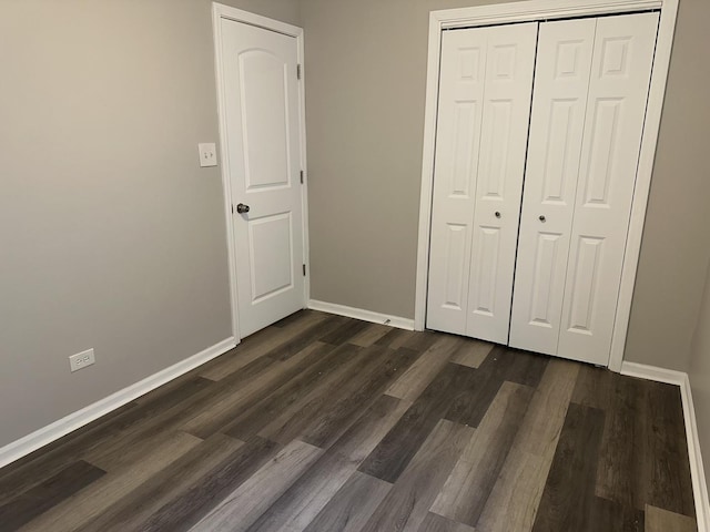 unfurnished bedroom with a closet and dark wood-type flooring