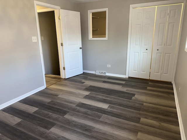 unfurnished bedroom featuring dark wood-type flooring and a closet