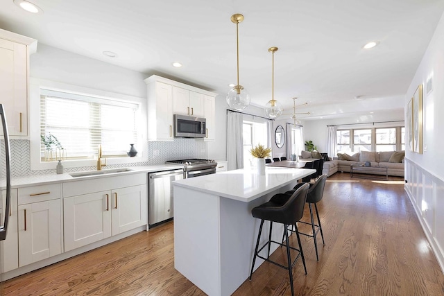 kitchen featuring sink, white cabinets, tasteful backsplash, a kitchen island, and stainless steel appliances