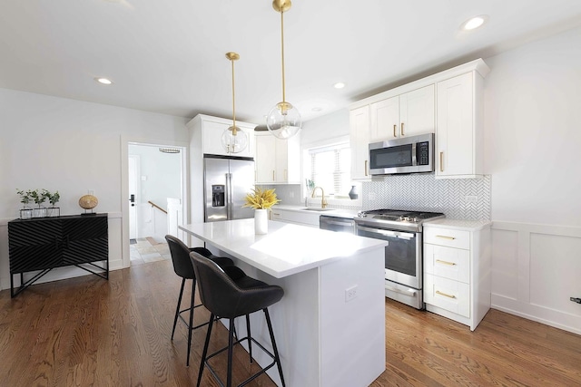 kitchen with a kitchen island, white cabinetry, hanging light fixtures, and appliances with stainless steel finishes