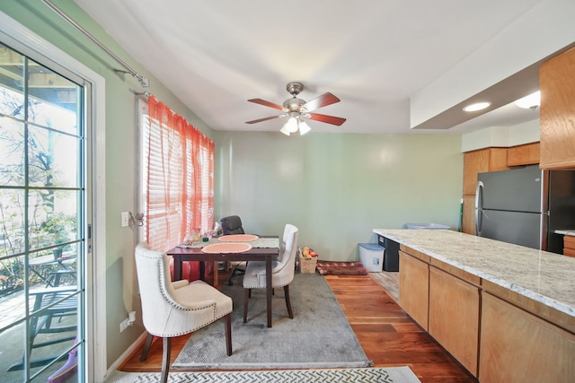 kitchen with ceiling fan, light stone countertops, dark hardwood / wood-style floors, and stainless steel refrigerator