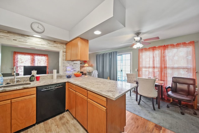 kitchen featuring dishwasher, kitchen peninsula, sink, light wood-type flooring, and light stone counters