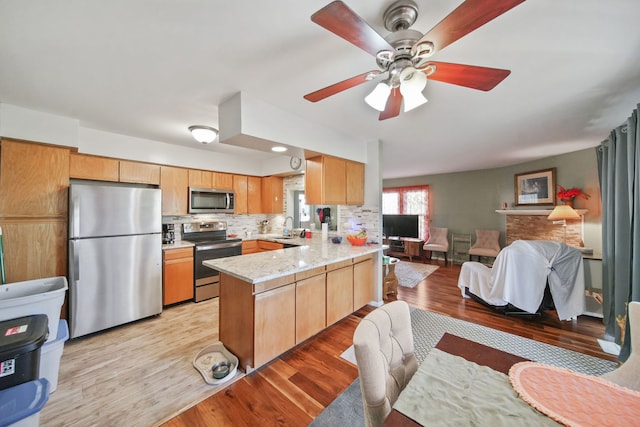 kitchen featuring stainless steel appliances, tasteful backsplash, light hardwood / wood-style floors, sink, and kitchen peninsula