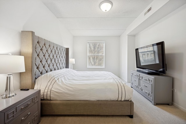 bedroom featuring light colored carpet and a textured ceiling