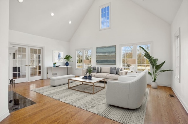 living room featuring wood-type flooring, high vaulted ceiling, and french doors