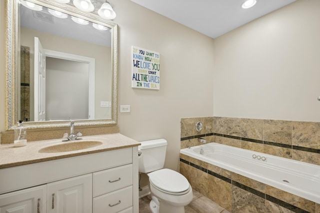 bathroom with vanity, tiled bath, and toilet