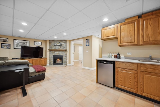 kitchen with a stone fireplace, sink, a paneled ceiling, and refrigerator