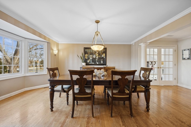 dining room with decorative columns, crown molding, light wood-type flooring, and french doors