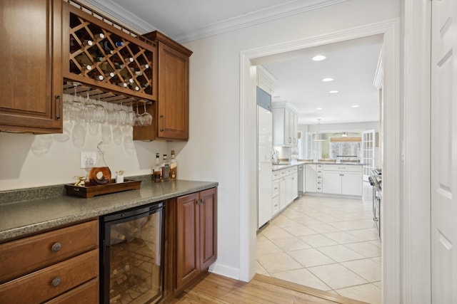 kitchen with light tile patterned floors, crown molding, sink, high end range, and wine cooler