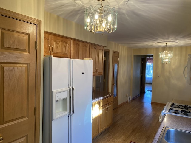 kitchen with an inviting chandelier, white appliances, decorative light fixtures, and dark hardwood / wood-style flooring