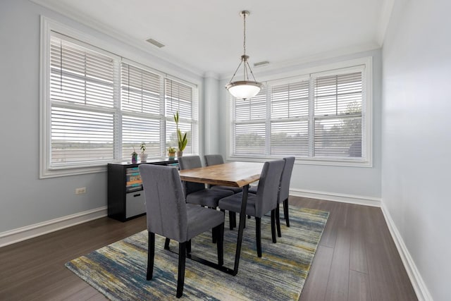 dining area featuring dark wood-type flooring and crown molding