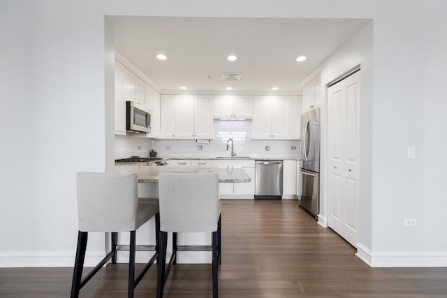 kitchen with white cabinetry, sink, light stone countertops, and appliances with stainless steel finishes