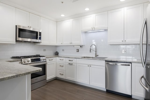 kitchen featuring sink, white cabinets, stainless steel appliances, light stone countertops, and dark wood-type flooring