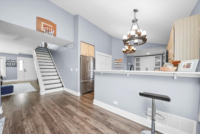 kitchen featuring high quality fridge, a kitchen breakfast bar, dark hardwood / wood-style floors, kitchen peninsula, and a notable chandelier