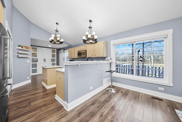 kitchen featuring stainless steel appliances, a kitchen breakfast bar, hanging light fixtures, dark hardwood / wood-style floors, and vaulted ceiling