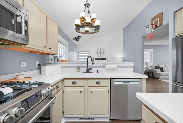 kitchen with appliances with stainless steel finishes, lofted ceiling, sink, a notable chandelier, and cream cabinets