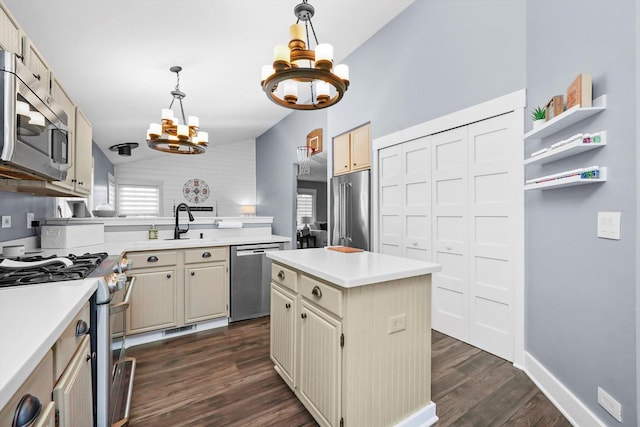 kitchen featuring hanging light fixtures, appliances with stainless steel finishes, a kitchen island, an inviting chandelier, and lofted ceiling