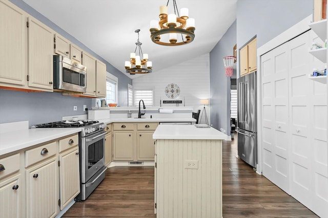 kitchen featuring appliances with stainless steel finishes, a kitchen island, dark wood-type flooring, a notable chandelier, and vaulted ceiling